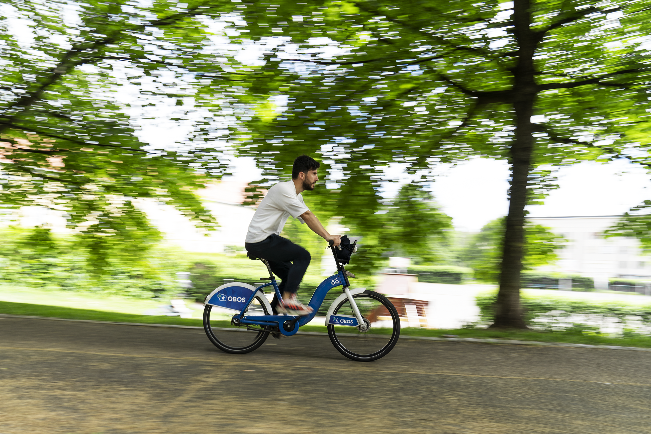 Young man riding an Oslo City bike in a park.